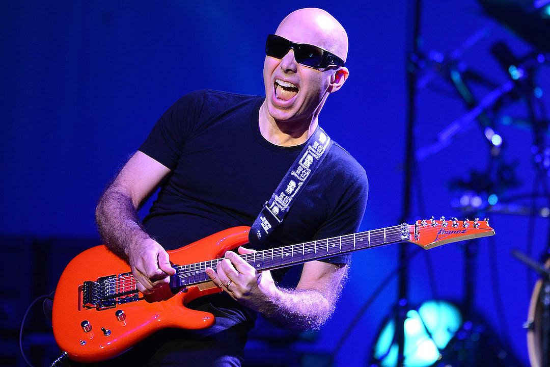 Joe Satriani ©Ethan Mille/Getty Images, Pour sa 12ème édition, le festival Guitare en Scène, monté par un groupe d’amis qui fait la part belle à l’instrument emblématique du rock, met une fois de plus la barre très haut avec son affiche de rêve : l’intemporel Sting, les enragés Black Rebel Motorcycle Club ou encore le virtuose Joe Satriani illumineront de leur charismatique présence la grande scène du chapiteau, parmi tant d’autres musiciens. Du point de vue du nombres de spectateurs (5000), le festival présente des dimensions modérées, contrairement à la grandeur de la programmation: cela rend l’interaction entre le public et les artistes d’autant plus forte et précieuse, une volonté assumée par les organisateurs. Souhaitant également mettre en avant les jeunes talents, ceux-ci ont monté un tremplin qui permet aux groupes sélectionnés une visibilité et des sensations sans pareil. Le festival organise aussi des masterclasses, offrant l’occasion à des passionnés de guitare (et de basse) de bénéficier de l’expérience de professeurs émérites. En somme, un événement qui résonne comme une ode à ces pincements de cordes, infinies sources d’émotions.